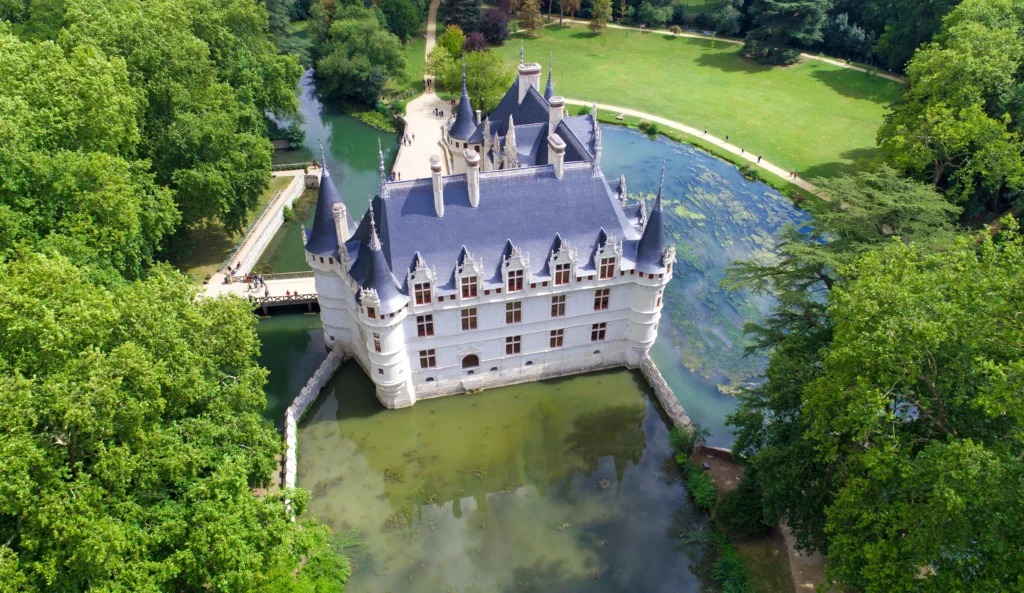 Vue aérienne du château d’Azay-le-Rideau entouré par les eaux de l’Indre et son parc arboré, révélant son implantation sur une île.
