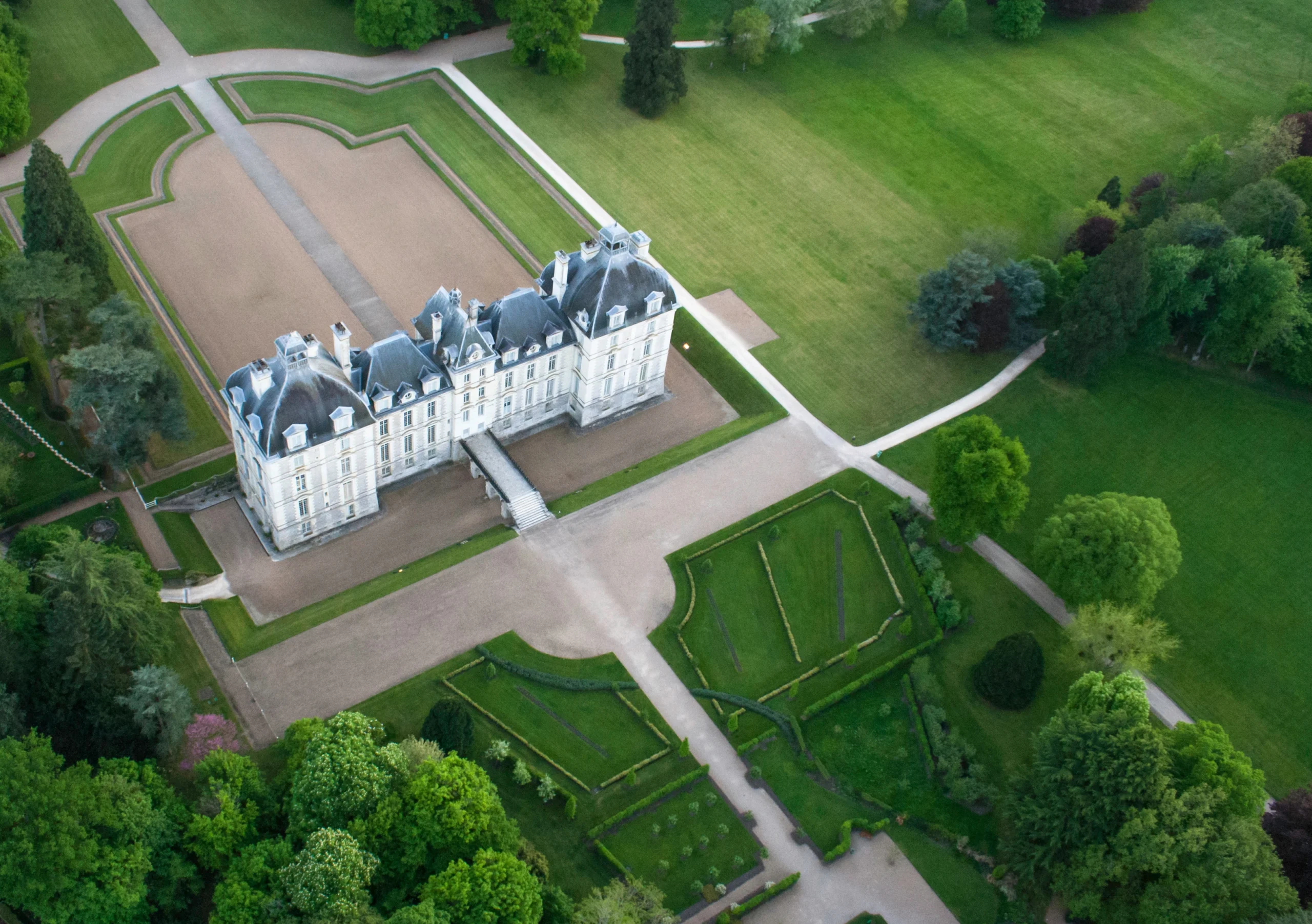 Vue aérienne du château de Cheverny entouré de son vaste parc paysager, de jardins géométriques et d’allées arborées au cœur du Val de Loire.