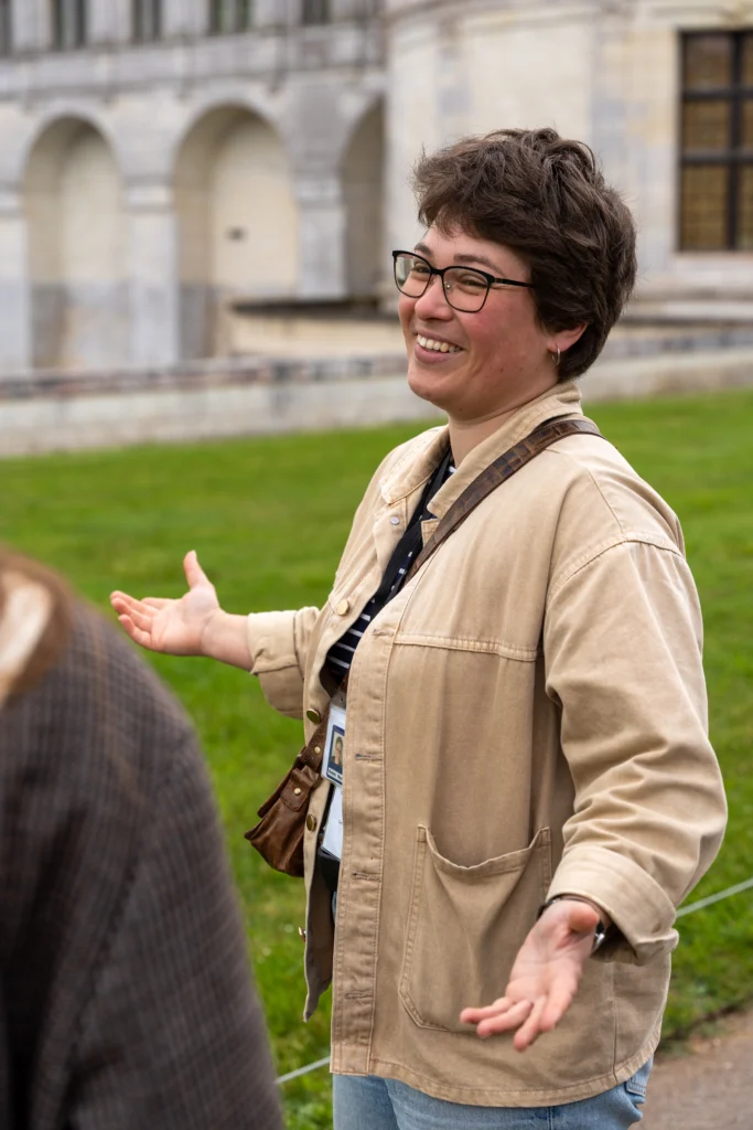 Guide conférencière souriante présentant le château de Chambord à un groupe de visiteurs lors d'une visite guidée en plein air.