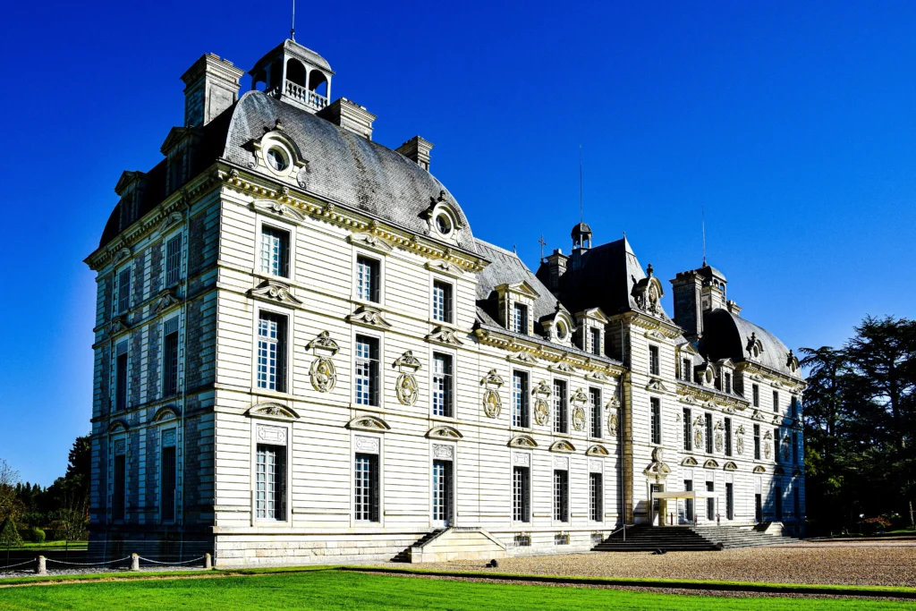 Façade principale du château de Cheverny sous un ciel bleu, mettant en valeur son architecture classique du XVIIe siècle et ses élégantes décorations sculptées.
