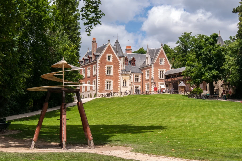 Vue du Château du Clos Lucé à Amboise avec une machine inspirée des inventions de Léonard de Vinci dans le parc lors d'une visite guidée.