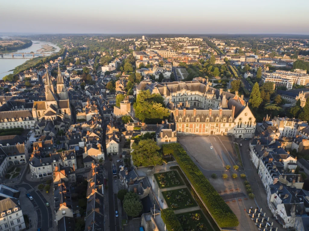 Vue aérienne du château royal de Blois, de l’église Saint-Nicolas et du centre historique avec la Loire en arrière-plan.