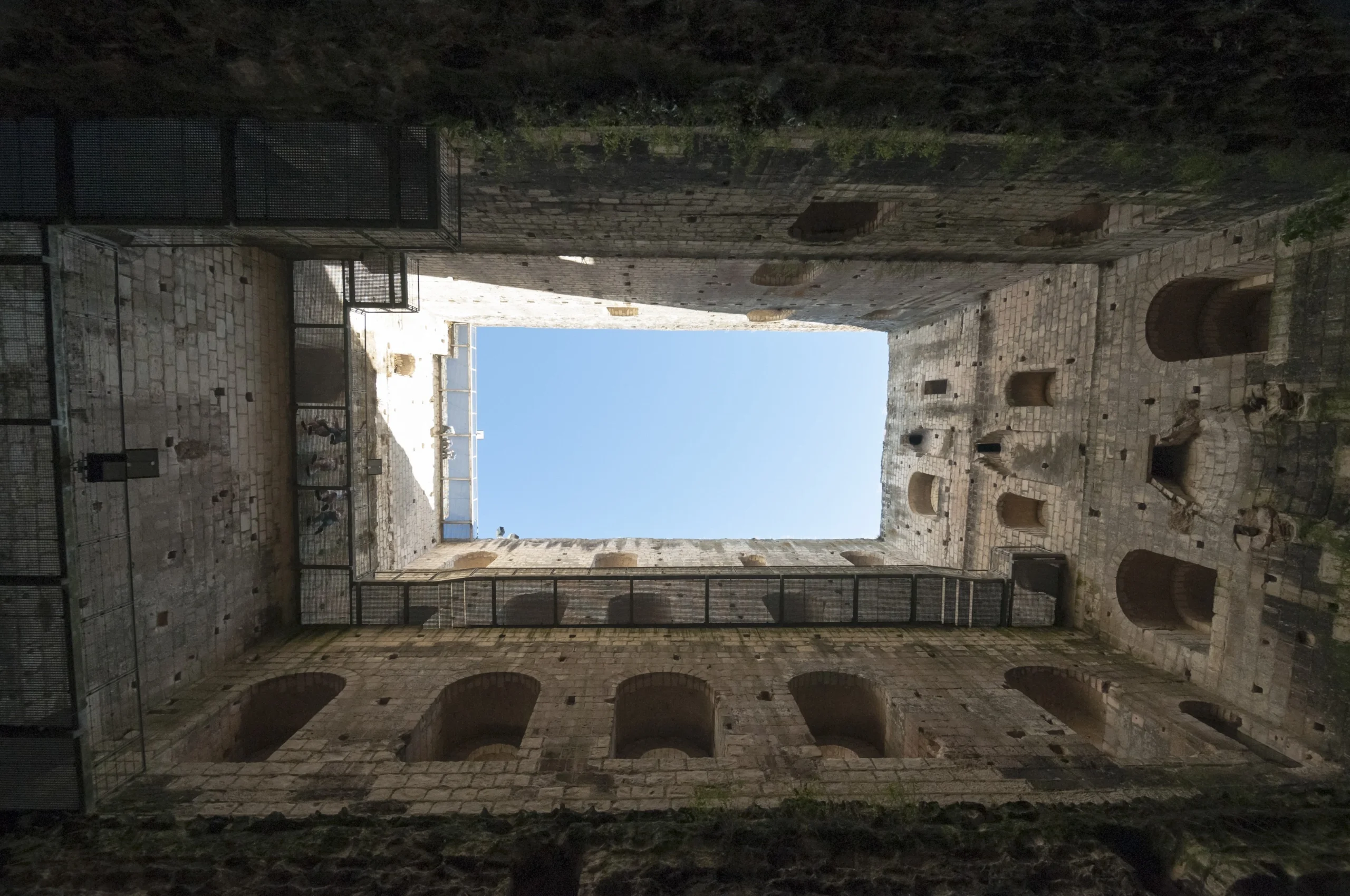 Vue intérieure du grand donjon de Loches, ouverte vers le ciel entre les hautes murailles médiévales en pierre.